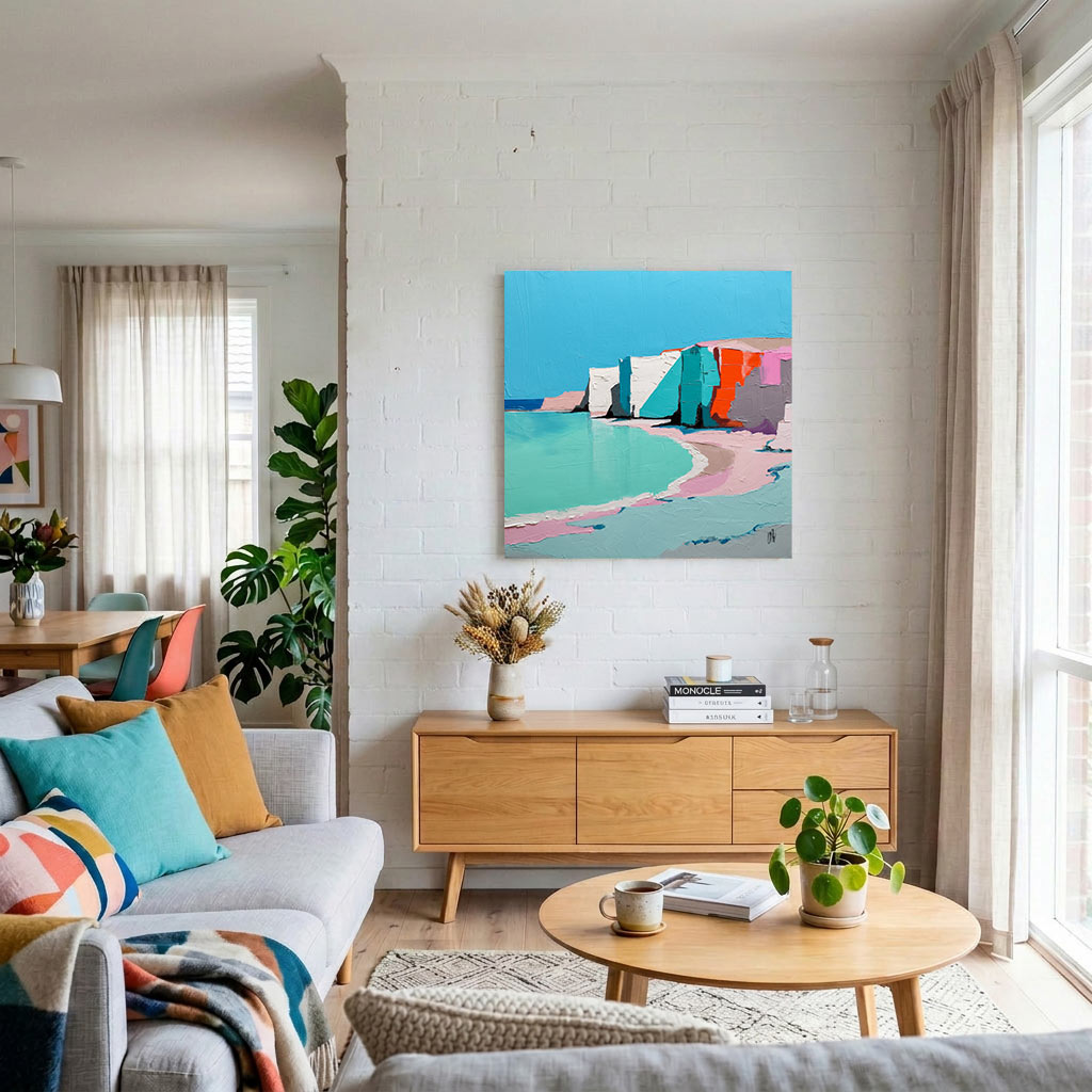 Living room with a white brick wall, a colorful abstract coastal painting above a wooden sideboard, and a round coffee table with plants and a cup nearby.