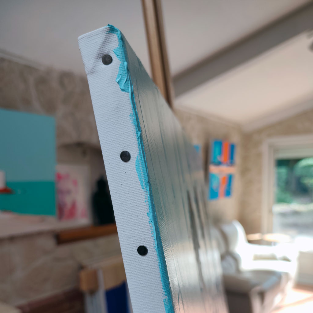 Zoom sur la tranche peinte en turquoise d'un tableau contemporain au couteau, détails des finitions sur les bords de la toile