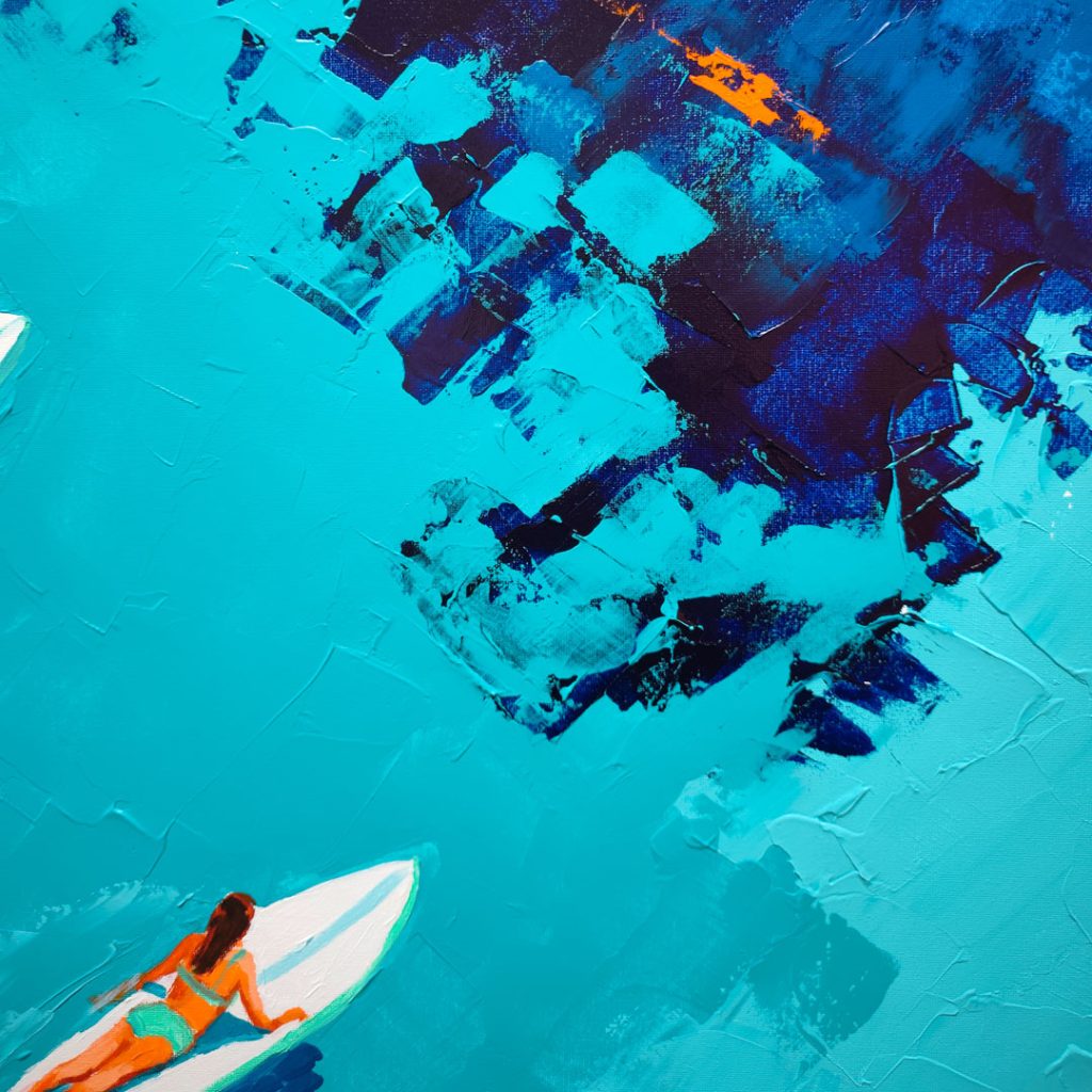 Zoom sur une surfeuse en maillot de bain orange et vert allongée sur sa planche blanche au milieu d'une eau turquoise texturée